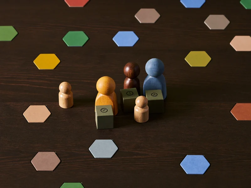 Joc de strategie în desfășurare, cu meepleuri din lemn și plăcuțe hexagonale.